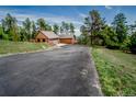 Long driveway leads to a cabin home nestled among trees, with a detached garage at 8624 S Doubleheader Ranch Rd, Morrison, CO 80465