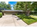 Single-story home with a spacious driveway, attached garage, and a well-kept front lawn and landscaping at 2934 S Columbine St, Denver, CO 80210