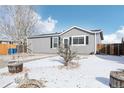 This home features new gray siding, black shutters, and a drought-resistant landscape with mature trees at 262 Apache Pl, Brighton, CO 80603