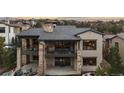 Impressive rear exterior showcasing a multi-story home with a stone facade, tiled roof, and outdoor living spaces at 8246 Raphael Ln, Littleton, CO 80125