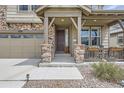 Inviting front porch with stone pillars, dark wood door, and a cozy seating area with charming decorations at 8133 Arapahoe Peak St, Littleton, CO 80125