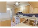 Functional kitchen with light wood cabinets, white appliances, and blue tile backsplash at 6776 S Holland Way, Littleton, CO 80128