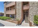 View of building's exterior with stone facade and wooden stairs leading to upstairs units at 4691 S Decatur St # 215, Englewood, CO 80110