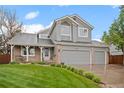 Charming gray two-story home with a three-car garage and lush green lawn at 8533 S Flower Ct, Littleton, CO 80128
