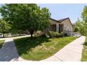 Landscaped corner lot with lush green lawn, mature trees, and decorative white picket fence at 24664 E Louisiana Cir, Aurora, CO 80018