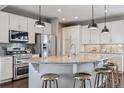 Bright, modern kitchen featuring white cabinets, stainless steel appliances, and a granite countertop island with seating at 2794 Lima St, Denver, CO 80238