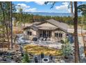 Stunning backyard featuring a patio, fire pit, manicured lawn, and scenic mountain views beyond the treeline at 878 Tree Bark Ter, Colorado Springs, CO 80132
