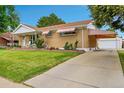 Suburban home with mature landscaping, a driveway, and a detached garage at 2121 W 73Rd Pl, Denver, CO 80221