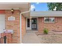 Brick home entrance featuring a walkway leading to the door and the house number is displayed at 8205 Pennsylvania St, Denver, CO 80229
