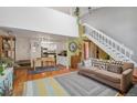 Spacious living room with hardwood floors, white staircase, and open layout to kitchen at 701 Harlan St # E29, Lakewood, CO 80214