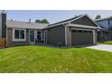 Inviting home featuring green siding, brick accents, and a well-maintained front yard at 12498 W Prentice Dr, Littleton, CO 80127