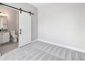 Bedroom with a sliding door to the bathroom and neutral carpet at 2078 S Holly St # 1, Denver, CO 80222