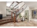 Inviting foyer features a stone accent wall, wooden beams, and an elegant staircase with iron railings at 3577 S Hillcrest Dr, Denver, CO 80237