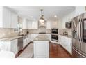 Spacious kitchen featuring white cabinets, granite countertops, stainless steel appliances, and a center island at 3577 S Hillcrest Dr, Denver, CO 80237