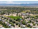 Expansive aerial view of a residential neighborhood, complete with green spaces, a school, and mountain views at 2548 Foothills Canyon Ct, Highlands Ranch, CO 80129
