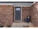Close-up of front entryway and door with brick facade and small chair at 1581 S Kendall St, Lakewood, CO 80232