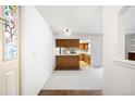 Bright room with white walls and carpet, an open floorplan to a kitchen with wood cabinets at 12560 E Warren Dr # E, Aurora, CO 80014