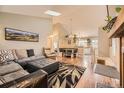 Open-concept living room with hardwood floors, a skylight, and seamless flow to dining area at 9689 W Chatfield Ave # H, Littleton, CO 80128