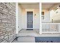 Gray front door with a white porch and stone accents at 13432 E 110Th Way, Commerce City, CO 80022
