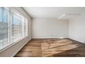 Spacious living room offers a large window, wood-look floors, and neutral colors at 8737 Santa Fe Dr, Thornton, CO 80260
