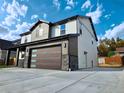 Angled view of a two-story home with stone accents and a spacious concrete driveway at 5550 Wetlands Dr, Longmont, CO 80504