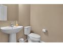 Clean, minimalist half bathroom featuring a pedestal sink, toilet, and neutral wall color at 7131 Shavano Cir, Frederick, CO 80504