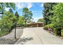 Long driveway leading up to a beautiful home with a large two car garage, surrounded by mature trees at 4790 W Lakeridge Rd, Denver, CO 80219