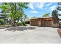 A large concrete driveway leads to a stone-accented two-car garage in this sunny exterior at 4790 W Lakeridge Rd, Denver, CO 80219