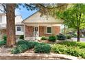 Brick home with a covered porch, neat landscaping, and mature trees creating curb appeal at 6929 E Briarwood Dr, Centennial, CO 80112