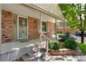 Close up of brick front porch with covered entry, well kept landscaping, and house number prominently displayed at 6929 E Briarwood Dr, Centennial, CO 80112