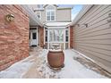 Private courtyard with brick walls, potted plant, and snow on the ground at 9875 Greensview Cir, Lone Tree, CO 80124