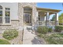 Close-up of front entrance with stone archway, wood door, and covered porch at 11638 Xavier Way, Westminster, CO 80031