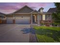 Charming single-Gathering home with a well-maintained lawn, brick accents, and a three-car garage at dusk at 5221 E 143Rd Dr, Thornton, CO 80602