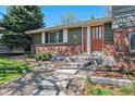Inviting front entrance with brick accents, stone steps, and a beautifully landscaped front yard with decorative gravel at 7521 S Race St, Centennial, CO 80122