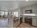 Bright kitchen features shaker cabinets, stainless steel appliances, granite countertops, and opens to the sunny living room at 10366 Uvalda Ct, Commerce City, CO 80022