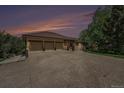The exterior of this house boasts a spacious three-car garage, set against the backdrop of a striking sunset at 7522 S Mount Zirkel, Littleton, CO 80127