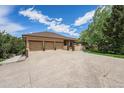 The exterior of this house boasts a spacious three-car garage, set against the backdrop of a blue sky at 7522 S Mount Zirkel, Littleton, CO 80127