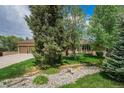 Charming front yard with lush lawn, mature trees, and a decorative rock feature creating a tranquil setting at 7522 S Mount Zirkel, Littleton, CO 80127