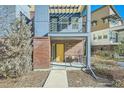 Inviting townhome entrance with a pergola-covered balcony, brick facade, and bright yellow front door at 11225 Colony Cir, Broomfield, CO 80021