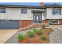 Eye-level home exterior with a colorful garden, brick accents, and gray garage door at 2176 S Welch Cir, Lakewood, CO 80228
