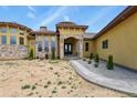 Custom home featuring a stone archway, lush landscaping, and inviting entryway at 634 County Road 37, Brighton, CO 80603