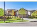 Inviting curb appeal with lush landscaping, beautiful trees, and a cozy front porch with an orange front door at 22646 E Glidden Dr, Aurora, CO 80016
