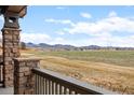 Scenic view from the porch with stone columns overlooking a sprawling field and distant mountains at 8555 W Quarles Pl, Littleton, CO 80128