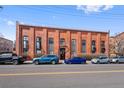 Exterior shot of building with brick facade, tall windows, and street parking at 3225 Blake St # 8, Denver, CO 80205