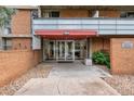 Apartment entrance features glass doors, red awning, and brick facade at 2500 S York St # 204, Denver, CO 80210