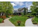 Expansive front yard featuring a pathway, lush lawn, mature trees, and manicured garden beds at 5080 Uinta St, Denver, CO 80238
