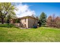 Well-maintained backyard featuring lush green grass, mature trees, and the home's brick exterior at 2615 Oak Dr # 7, Lakewood, CO 80215