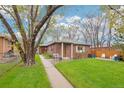 Charming brick home with a well-manicured lawn and mature trees, featuring a cozy outdoor seating area at 2459 S Corona St, Denver, CO 80210