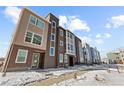 Modern townhome exterior featuring clean lines and a sidewalk with a ramp in a snowy landscape at 14241 Currant St, Broomfield, CO 80020