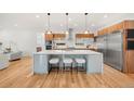 Open kitchen featuring an island with seating, stainless steel appliances, and modern wood cabinetry at 1490 S Vine St, Denver, CO 80210